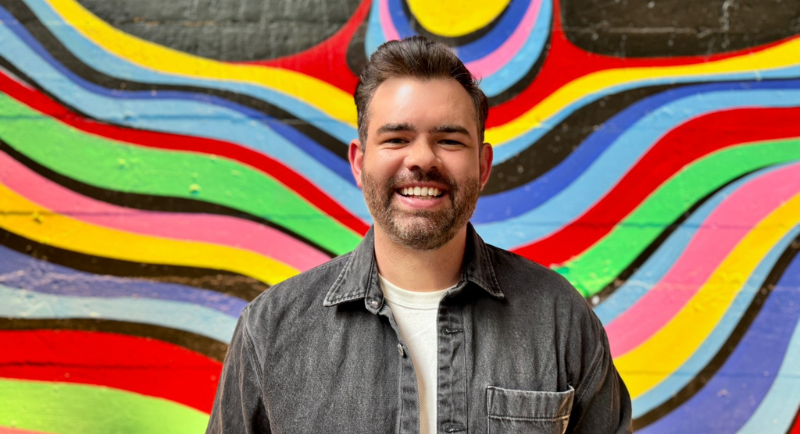 Neil Griffiths standing in front of a colourful wall