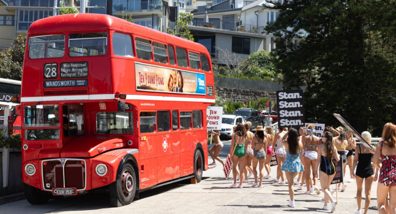 Red London bus with protestors publicising Ten Pound Poms