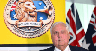 Clive Palmer standing behind a poster