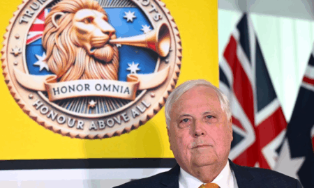 Clive Palmer standing behind a poster