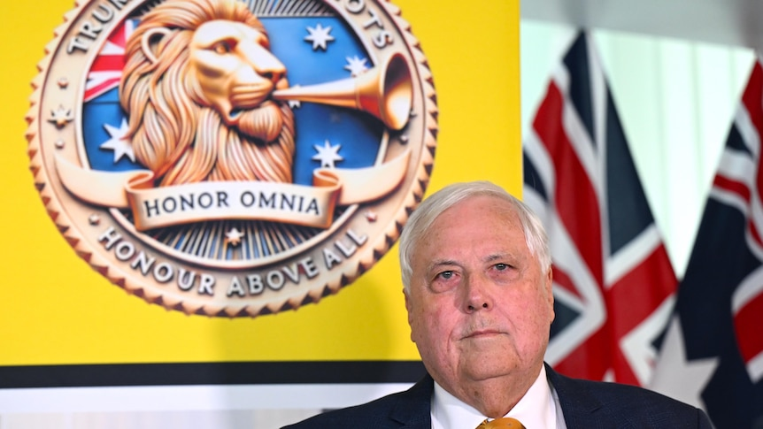 Clive Palmer standing behind a poster