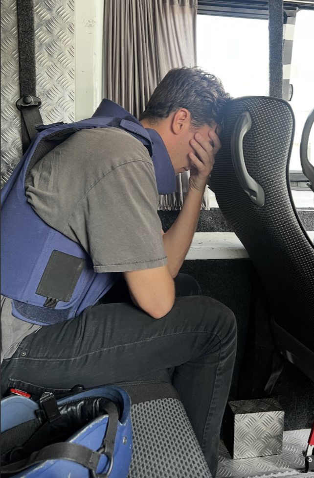 David Woiwood puts his head in his hands while sitting on a bus during his time covering the conflict in the Middle East