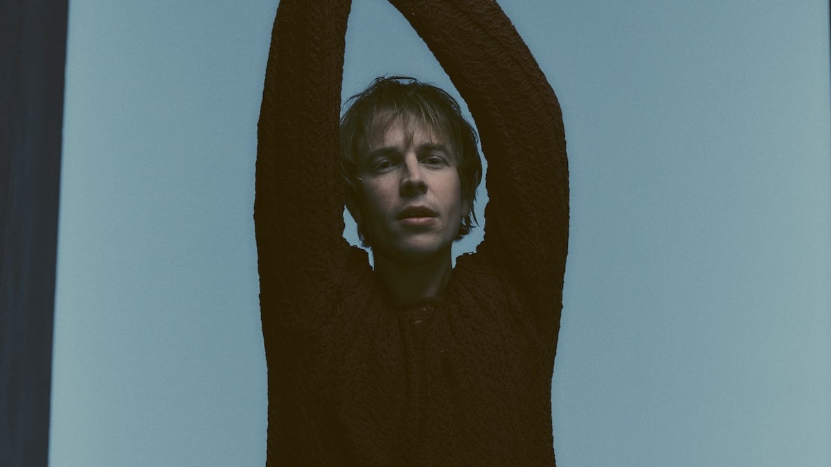 Tom Odell posing with his arms up