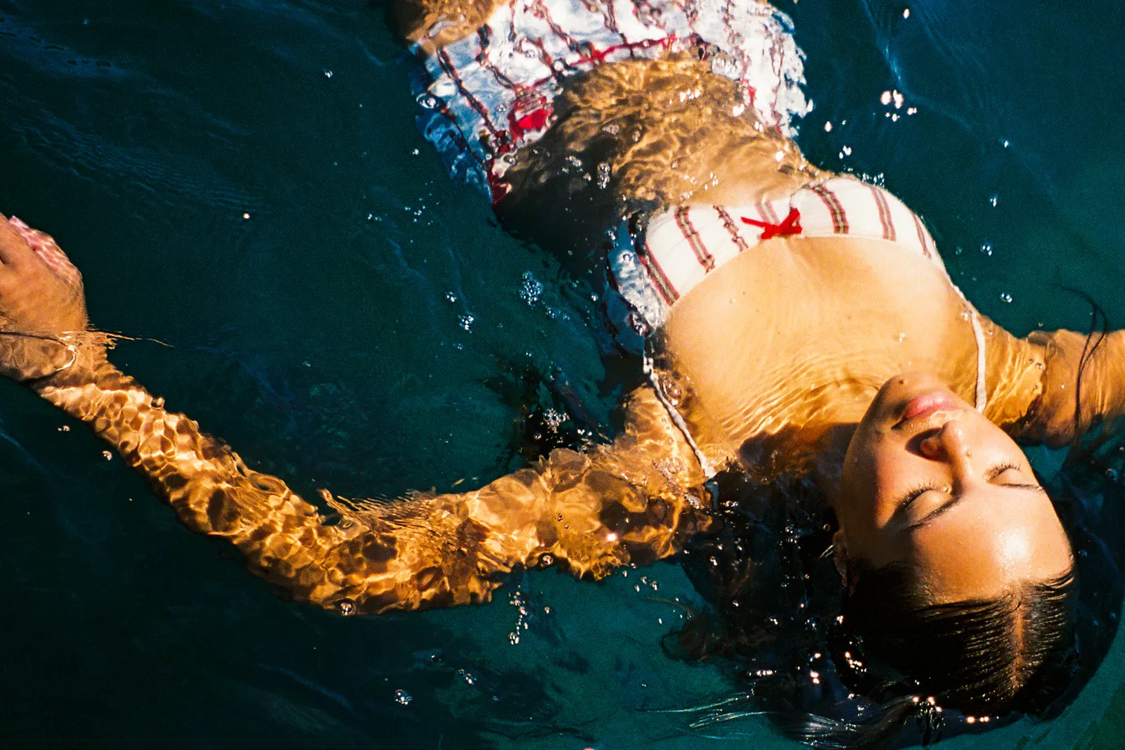 RIIKI REID wearing a white and red bikini floating in a body of water