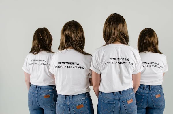 Four young women, backs to the camera, wearing white t-shirts with Remembering Barbara Cleveland on the back