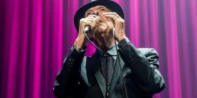 The late, great Leonard Cohen, sings live in trademark hat in front of purple curtains