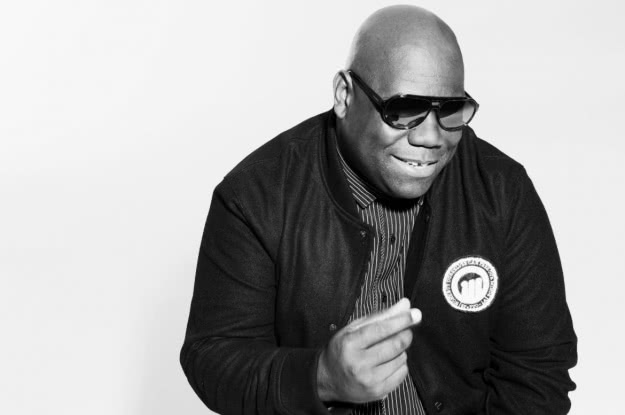 Carl Cox snapping his fingers, wearing dark sunglasses and a black bomber jacket
