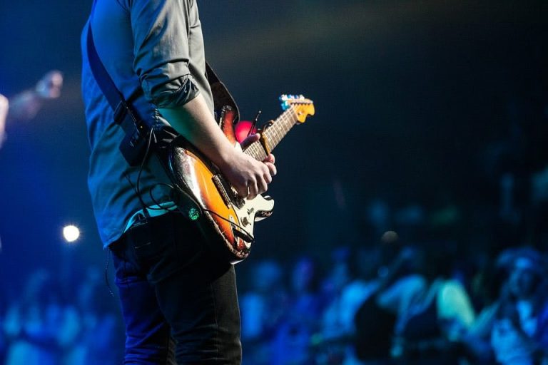 A guitarist performs onstage in front of a crowd