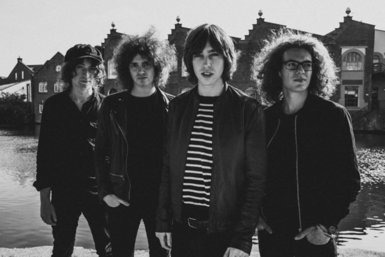 The four members of British rock band Catfish And The Bottlemen standing next to a river.