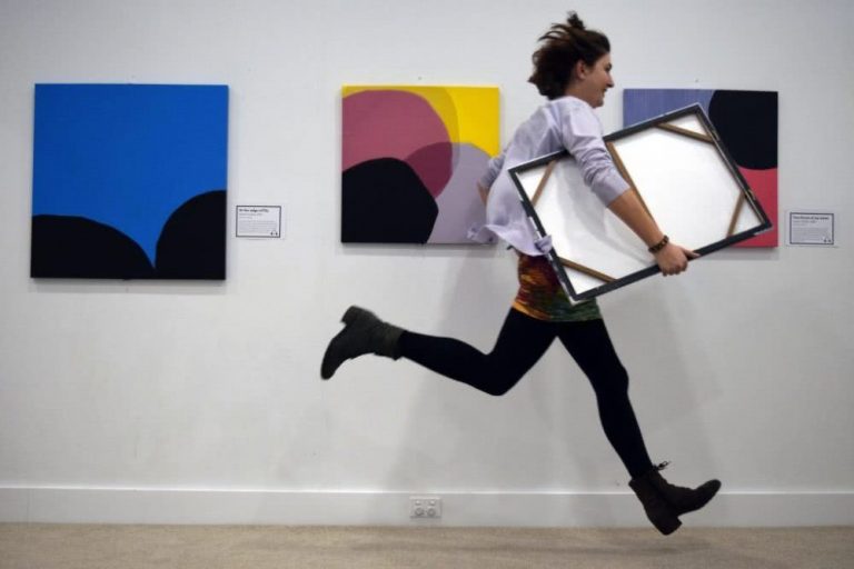 A young woman rushes out of a gallery with a stolen painting under her arm.