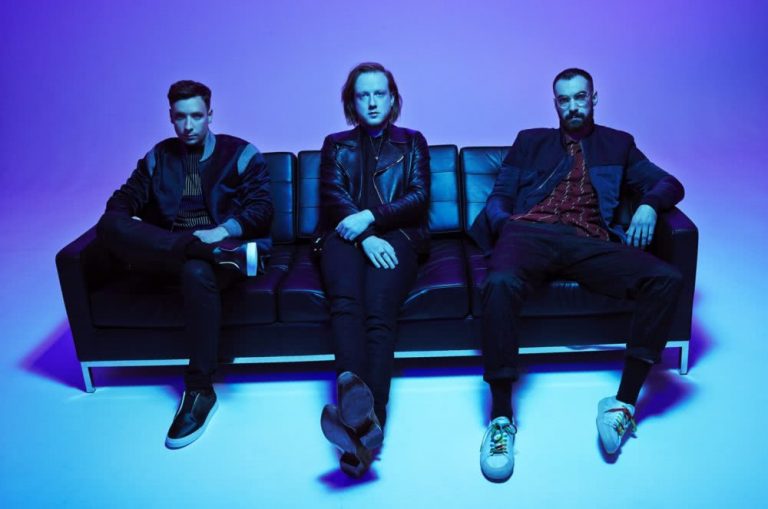 The members of Two Door Cinema Club, seated in what is presumably a Drake music video.