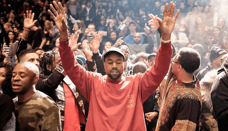 Kanye West raising his hands in front of a crowd