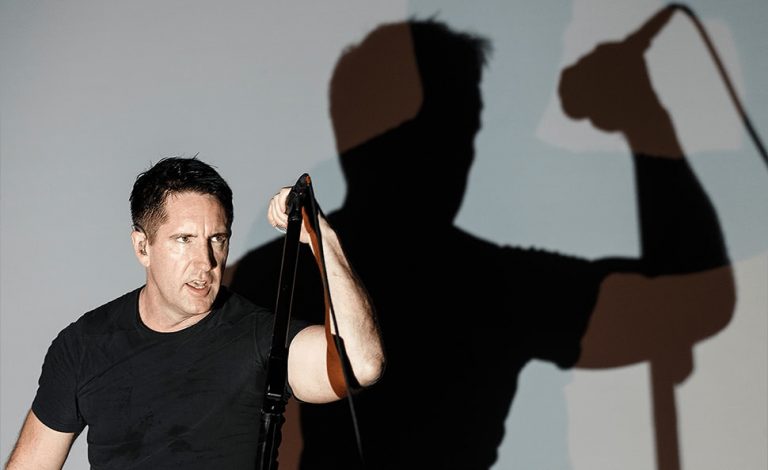 Nine Inch Nails' Trent Reznor playing live, with his shadow behind him