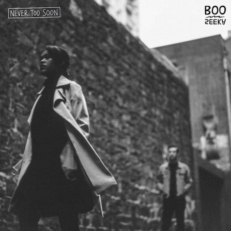 Boo Seeka's debut album Never Too Soon, featuring a grainy photo of a woman in a long beige jacket