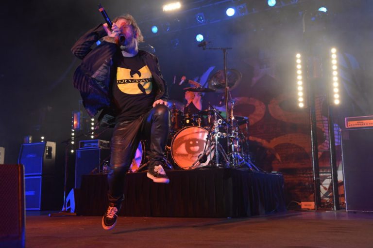 Corey Taylor of Stone Sour leaps about in front of the drum kit, Wu Tang shirt prominent