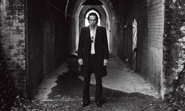 Nick Cave stares out from a dark corridor