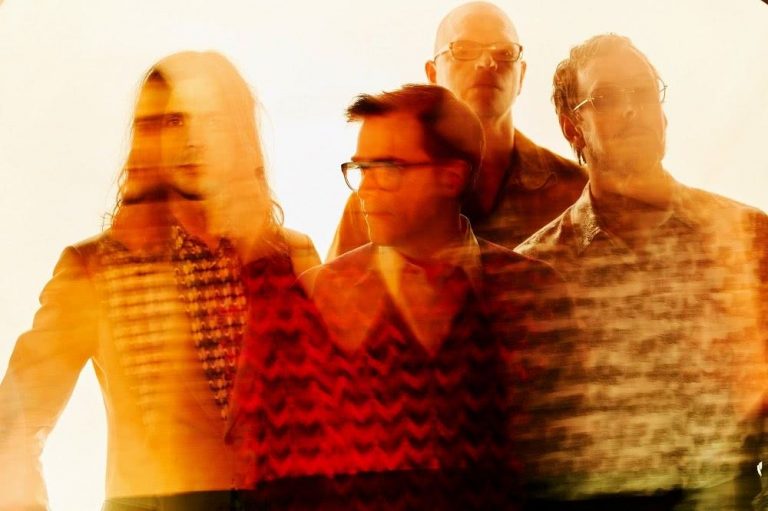 The members of Weezer standing in the sunset