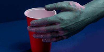 A zombie hand reaches for a red plastic cup