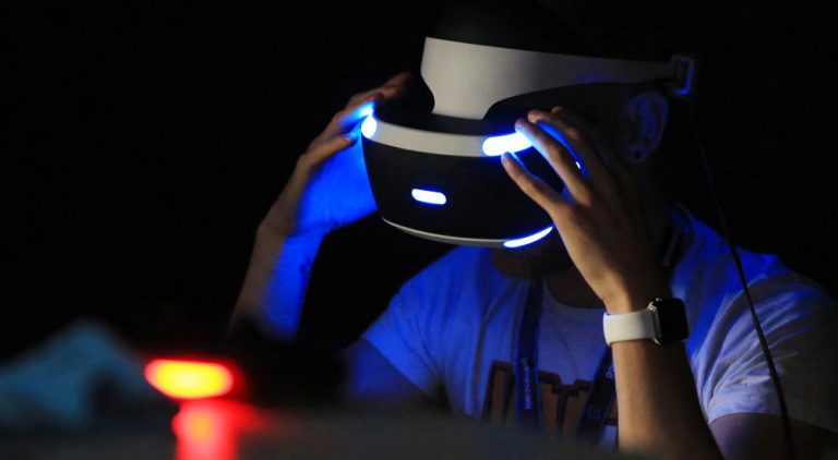 A man weraing a PlayStation VR headset in the dark