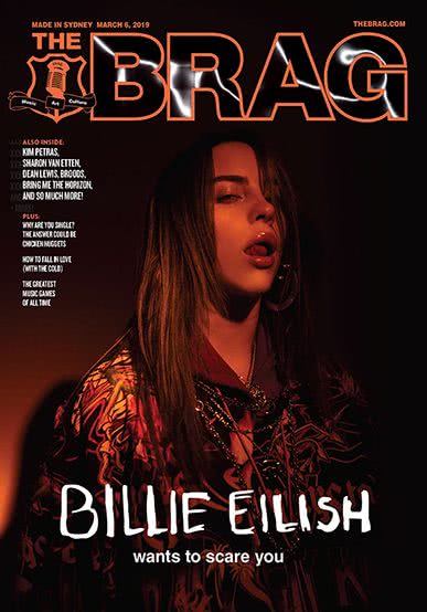 Billie Eilish on dark background cover of the Brag magazine with her tongue licking her lips