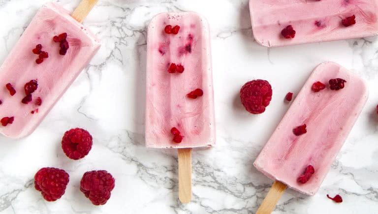 Raspberry popsicles on a white marble background