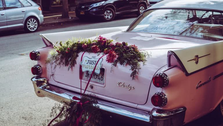 Photo of a pink wedding car with a 'just married' sign on it.