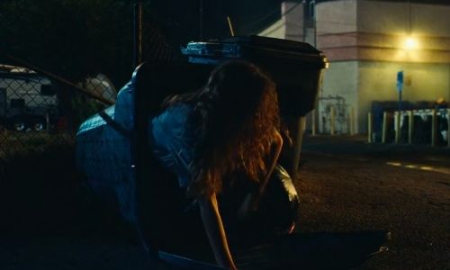 Rue climbs out of a bin