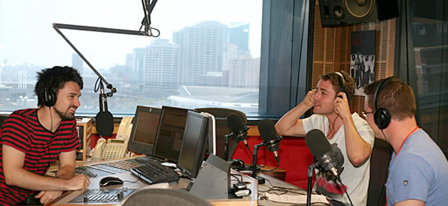 three men sitting in a studio talking into microphones