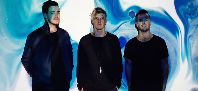 Rufus band members wearing black standing in front of a blue and white wall
