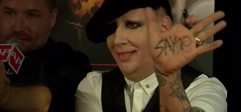 Marilyn Manson with black and white shite holding his hand out