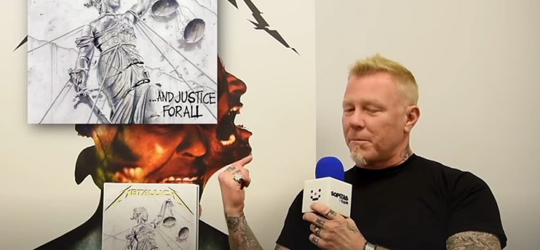 Man in black t-shirt talking into microphone looking at artwork