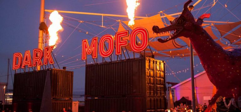 Dark Mofo sing lit up standing on containers with fire and a dragon statue