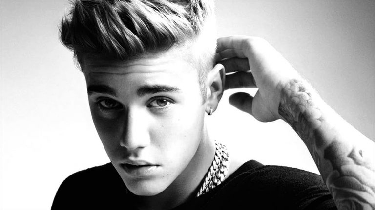 Black and white image of Justin Bieber with his hand behind his head.