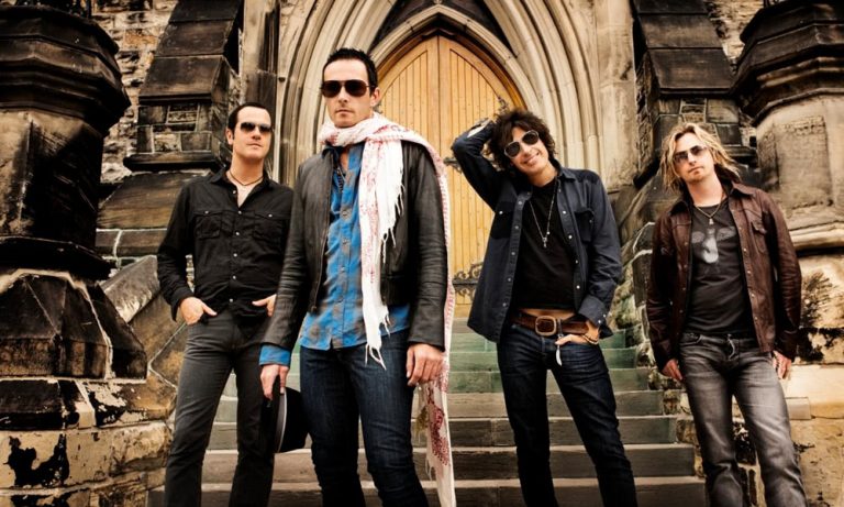 Four Band members from Stone Temple Pilots standing infant of an old building looking at the camera