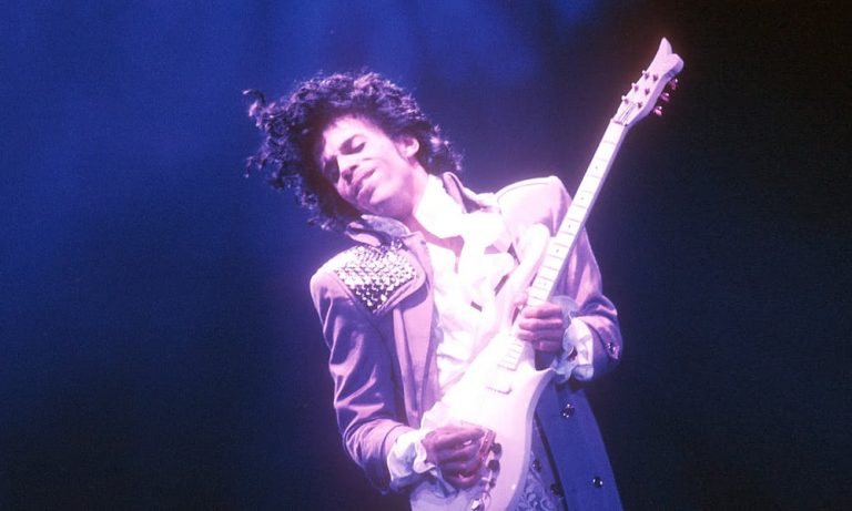 Prince plays his guitar onstage