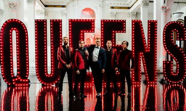 QOTSA stand in front of a huge 'QUEENS' sign