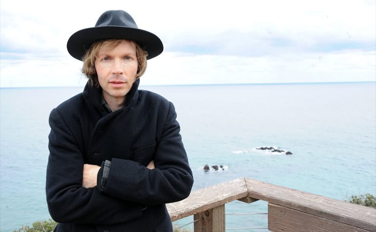 Legendary alt-rocker Beck, standing with the ocean in the background