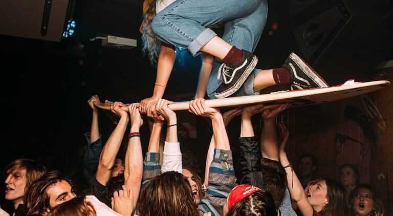 A member of Stork riding a surf board on a mosh pit