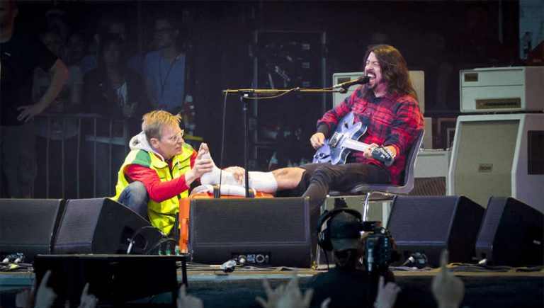 Dave Grohl being attended to by a medic after breaking his leg