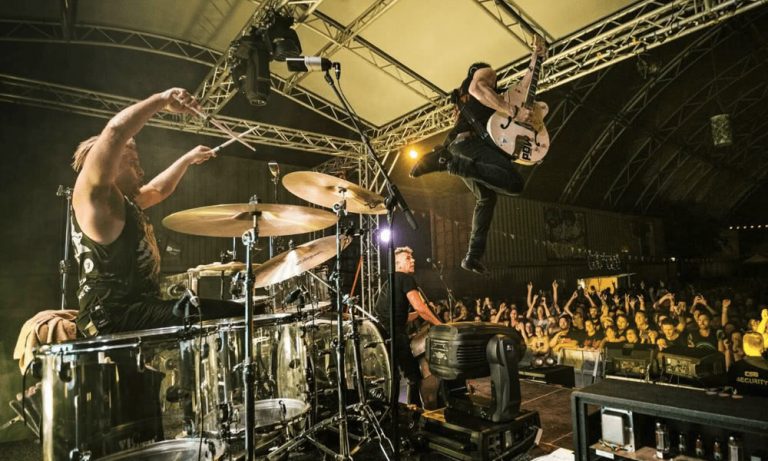 The Living End's Chris Cheney leaps in the air onstage
