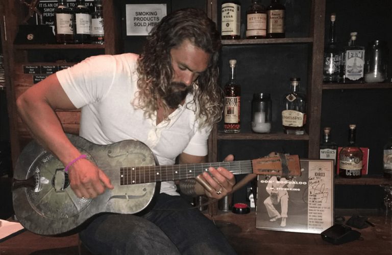 US actor Jason Momoa playing a guitar owned by C.W. Stoneking