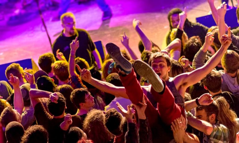 A punter crowd-surfs in a mosh pit