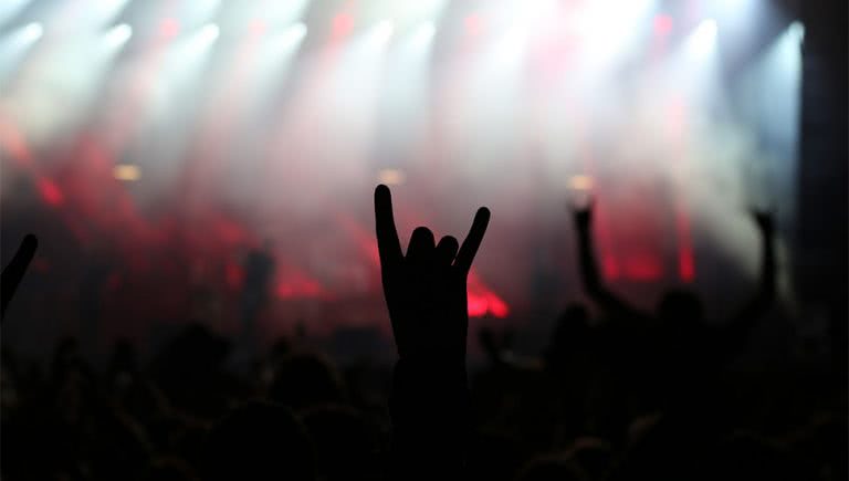 Image of a fan doing devil horns at a heavy metal concert