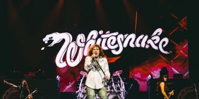 Whitesnake performing in front of their logo