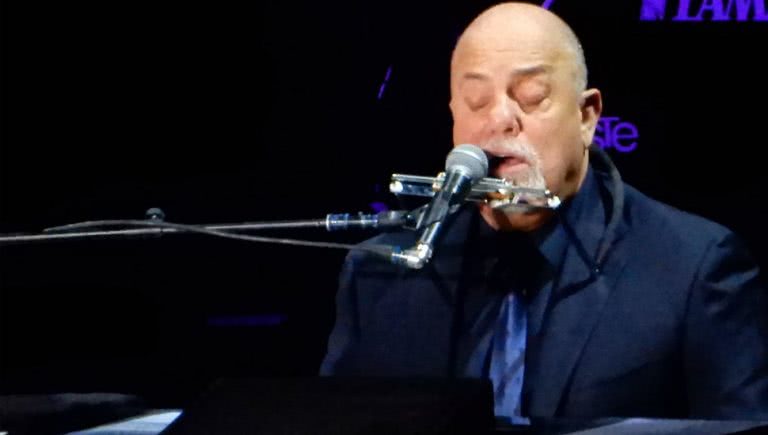 Iconic singer-songwriter Billy Joel playing piano and singing.